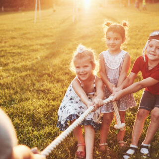 Children play with dad in the park. They pull the rope and have fun laying on a sunny day Children play with dad in the park. They pull the rope and have fun laying on a sunny day.