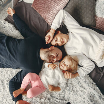 Cute family at home. Beautiful mother in a white sweater. Father with little daughter.