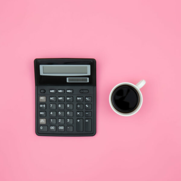 Calculator and coffee cup on pink background, flat lay, conceptual minimalism.